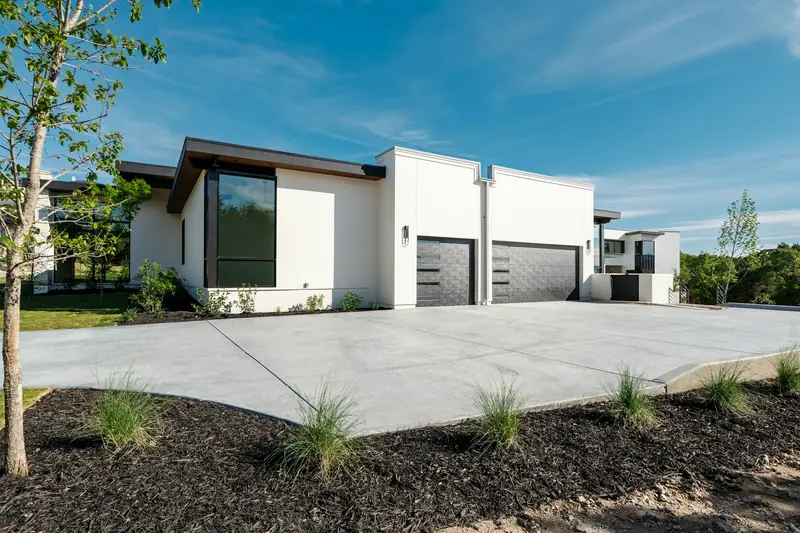 Wide new concrete driveway in front of a modern home with a three-car garage