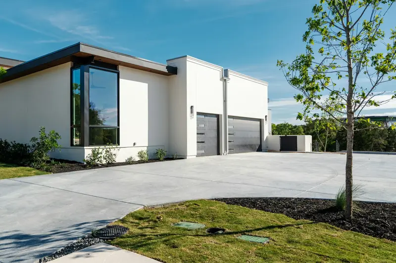Curving concrete driveway leading to a modern home's garages